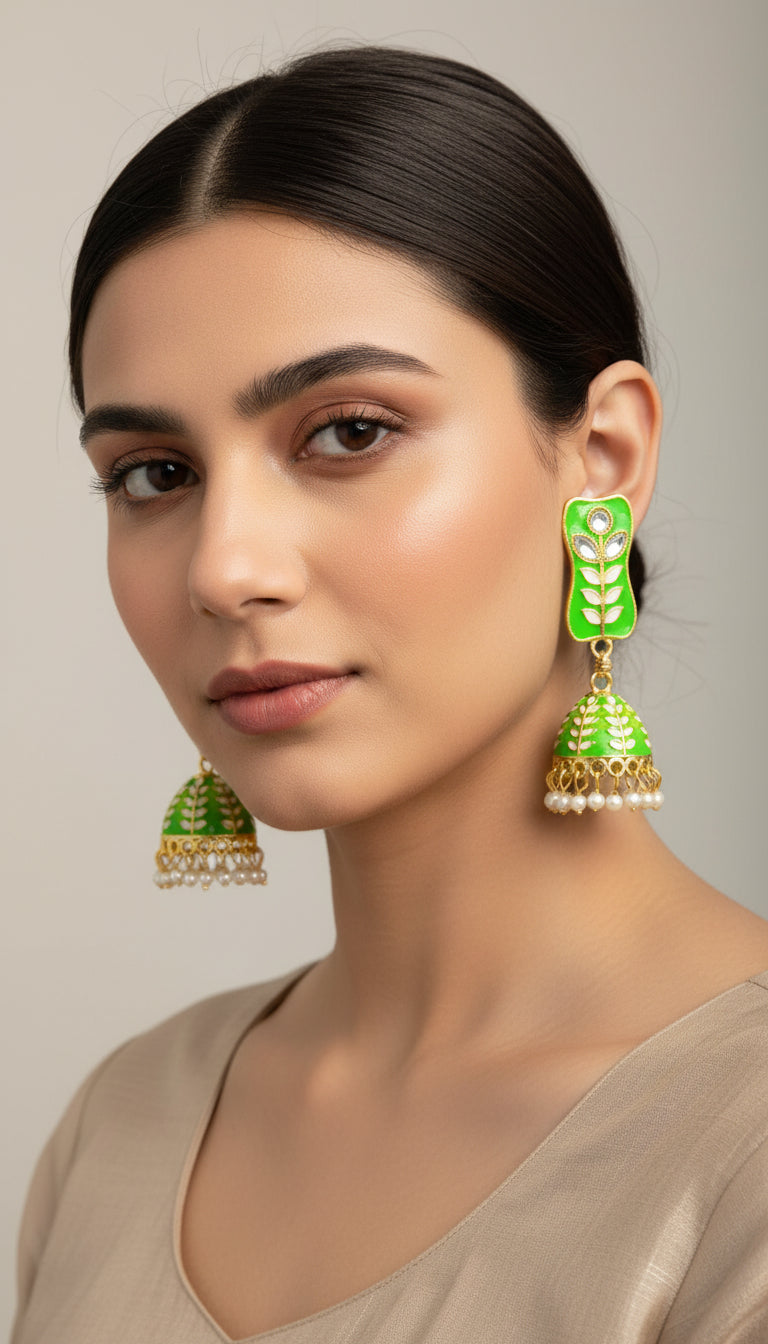 A pair of gold-plated green colour Meenakari drop Jhumka earrings displayed on a stand, featuring intricate designs and studded with stones.