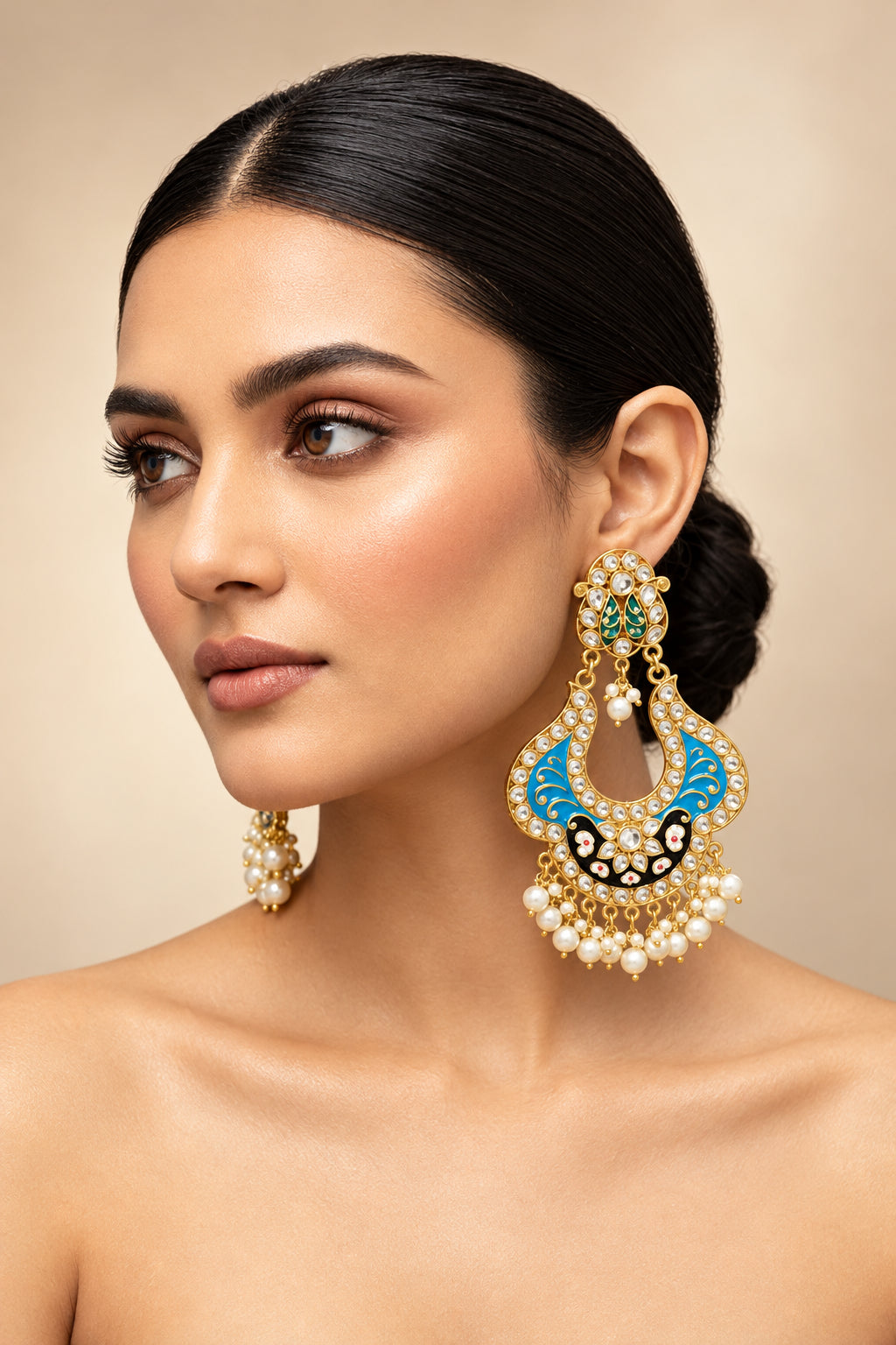 A pair of gold-toned chandbali earrings with blue and black minakari and kundan studded details along with pearls.