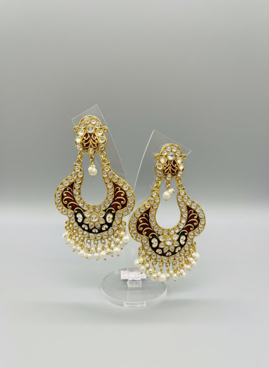 A pair of gold-toned chandbali earrings with maroon and black minakari and kundan studded details along with pearls. Party wear.