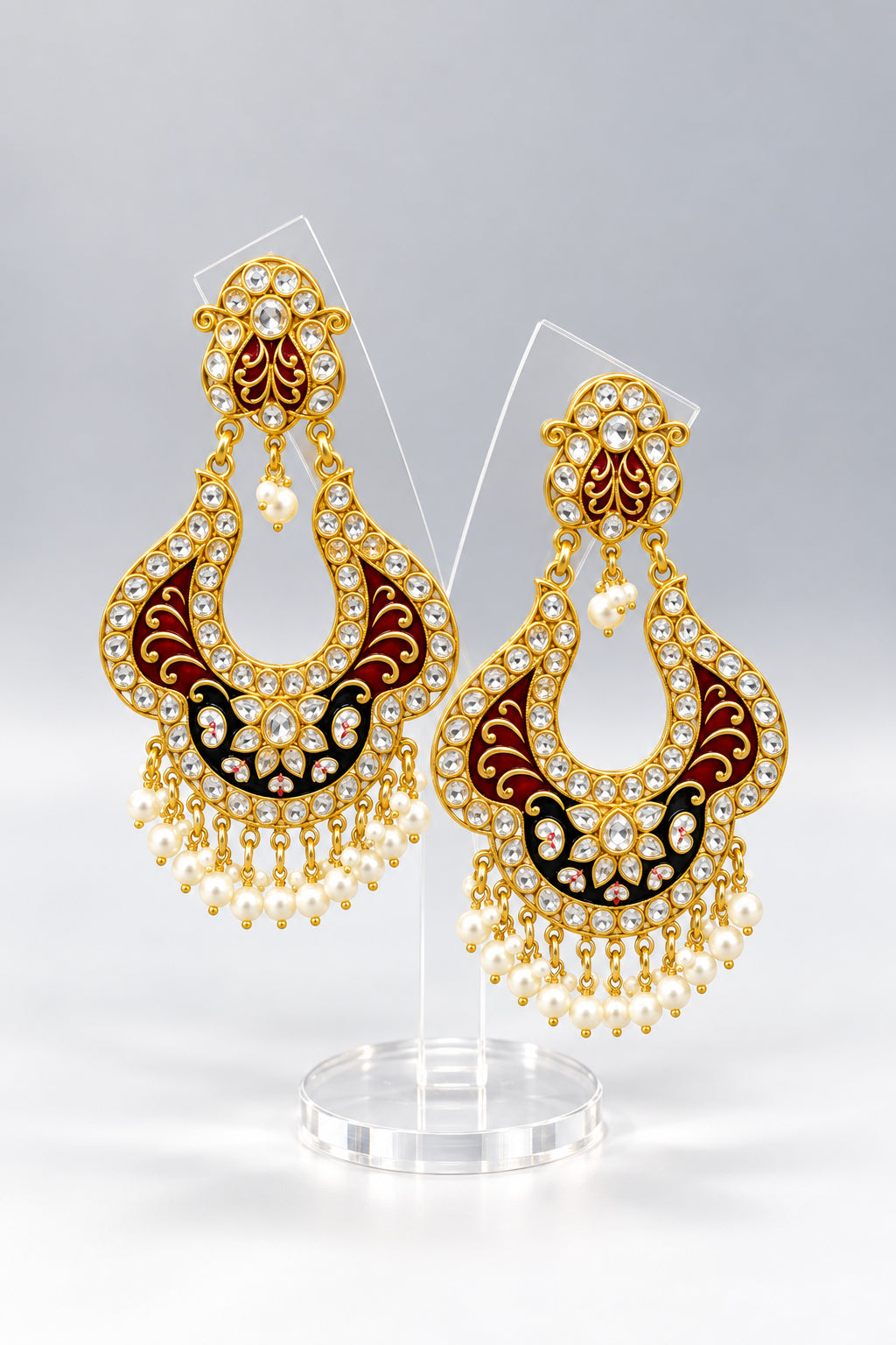 A pair of gold-toned chandbali earrings with maroon and black minakari and kundan studded details along with pearls. Party wear.