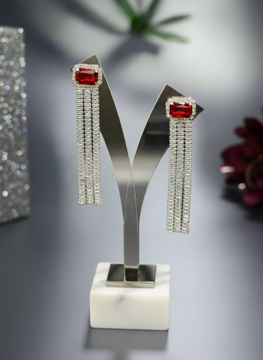 A pair of silver finish cubic zirconia drop earrings with red doublet semi precious stones. Party wear earrings.