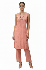 A woman modeling a sleeveless peach-pink embroidered kurta with matching wide-leg trousers, styled with a turquoise beaded necklace and nude heels against a plain white background.