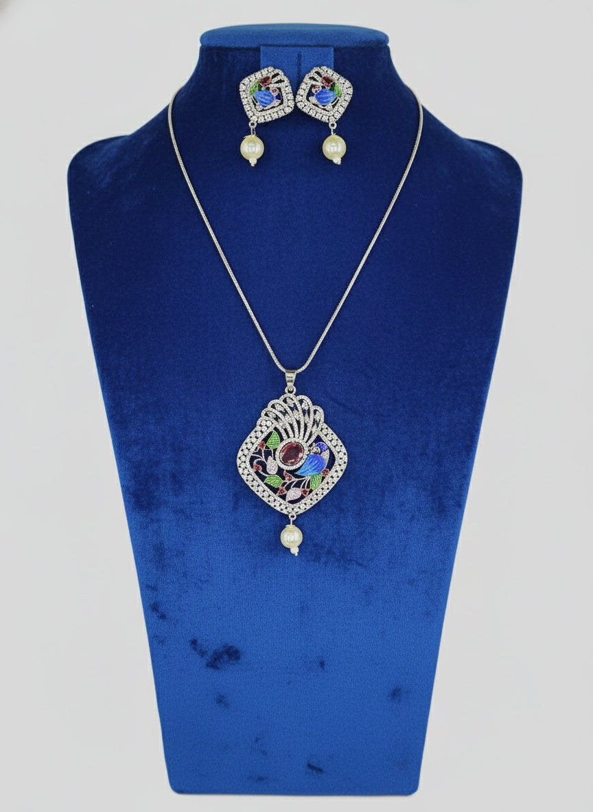 A peacock-shaped pendant necklace with blue, green, and gold enamel accents and white faux pearls, accompanied by matching earrings, displayed on a black mannequin bust.