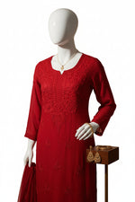 A red long-sleeve kurtiwith tonal floral embroidery, hanging on a white hanger against a black background.