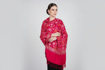 A red pashmina scarf with Kashmiri embroidery in a floral pattern, featuring tassels on the ends.