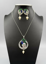 A rhodium-silver plated brass pendant with a peacock design accompanied by earrings, featuring vibrant green, blue, and gold enamel accents, as well as sparkling white and bottle green ad crystal embellishments. Party wear jewellery set.