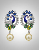 A rhodium-silver plated peacock design accompanied earrings, featuring vibrant green, blue and yellow enamel accents, as well as sparkling white and blue AD crystal stones. Earrings design is focused. Party wear earrings.