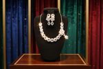 A set of American diamond jewellery consisting of a necklace and earrings with 3D floral elements, featuring white stones.