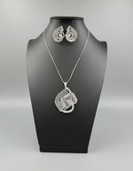 A set of artificial white AD stones pendants with earrings, featuring a geometric design with intricate detailing, displayed on a mannequin.