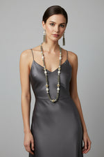 A set of jewellery featuring a long necklace with grey-coloured glass beads and metallic accents, paired with matching earrings, displayed on a mannequin bust.