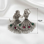 A silver-toned decorative wall plaque depicting two traditional dancing women, shown on a white background with a dimension marker indicating a height of 6.0 cm.
