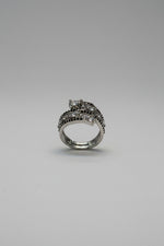 A silver-toned ring with dark, textured detailing sits on a digital scale displaying 5 grams.