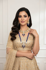 A traditional bridal necklace and matching earrings set displayed on a mannequin, featuring blue and gold colours with kundan stone intricate detailing and pearl beads.