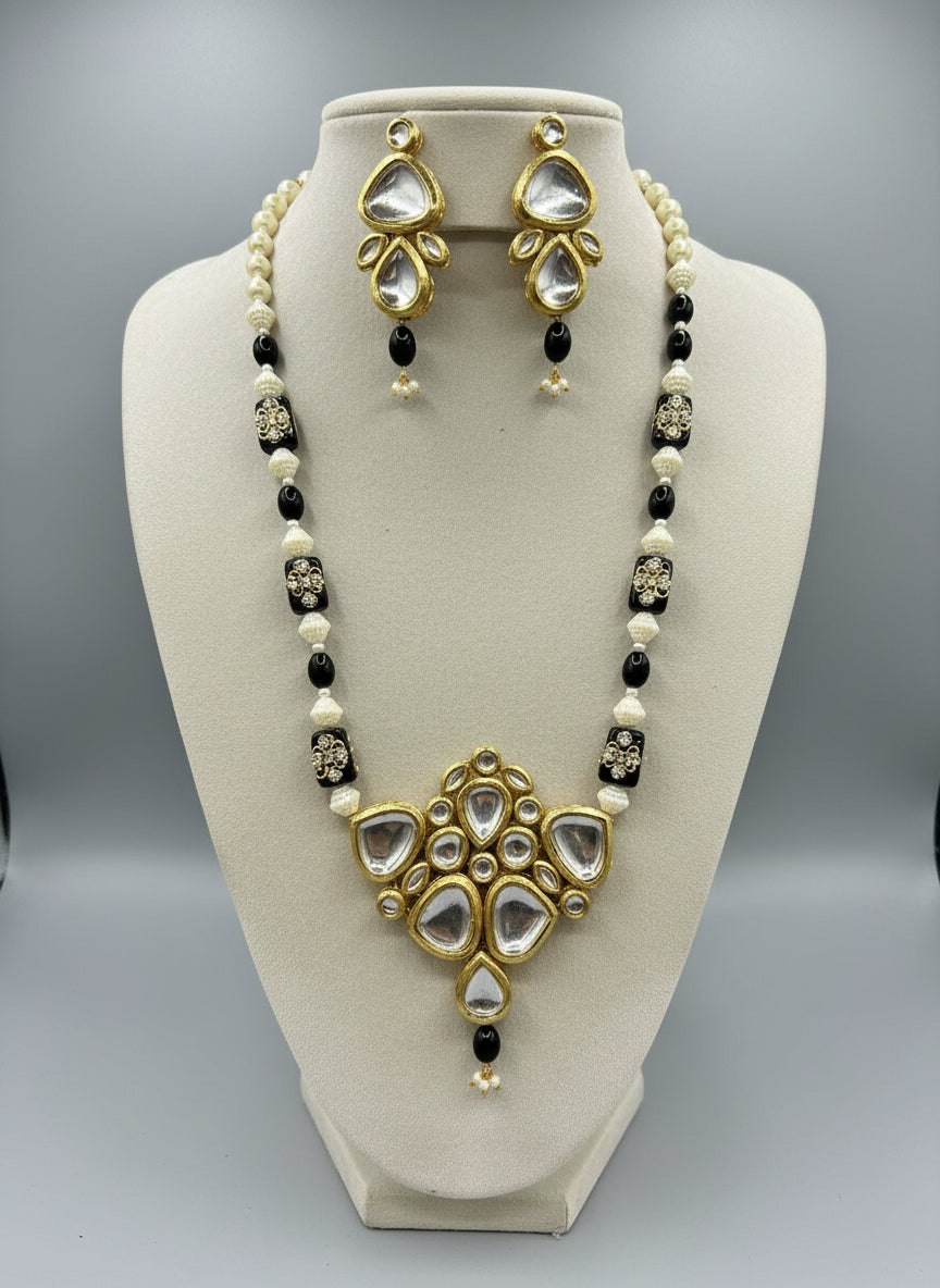 A traditional bridal necklace set displayed on a mannequin, featuring black and gold colors with intricate detailing and pearl beads.