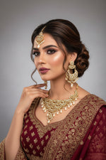 A traditional bridal necklace set featuring drop pearls and oval Kundans, with matching earrings and a maang tikka, displayed on a mannequin. Party wear set.