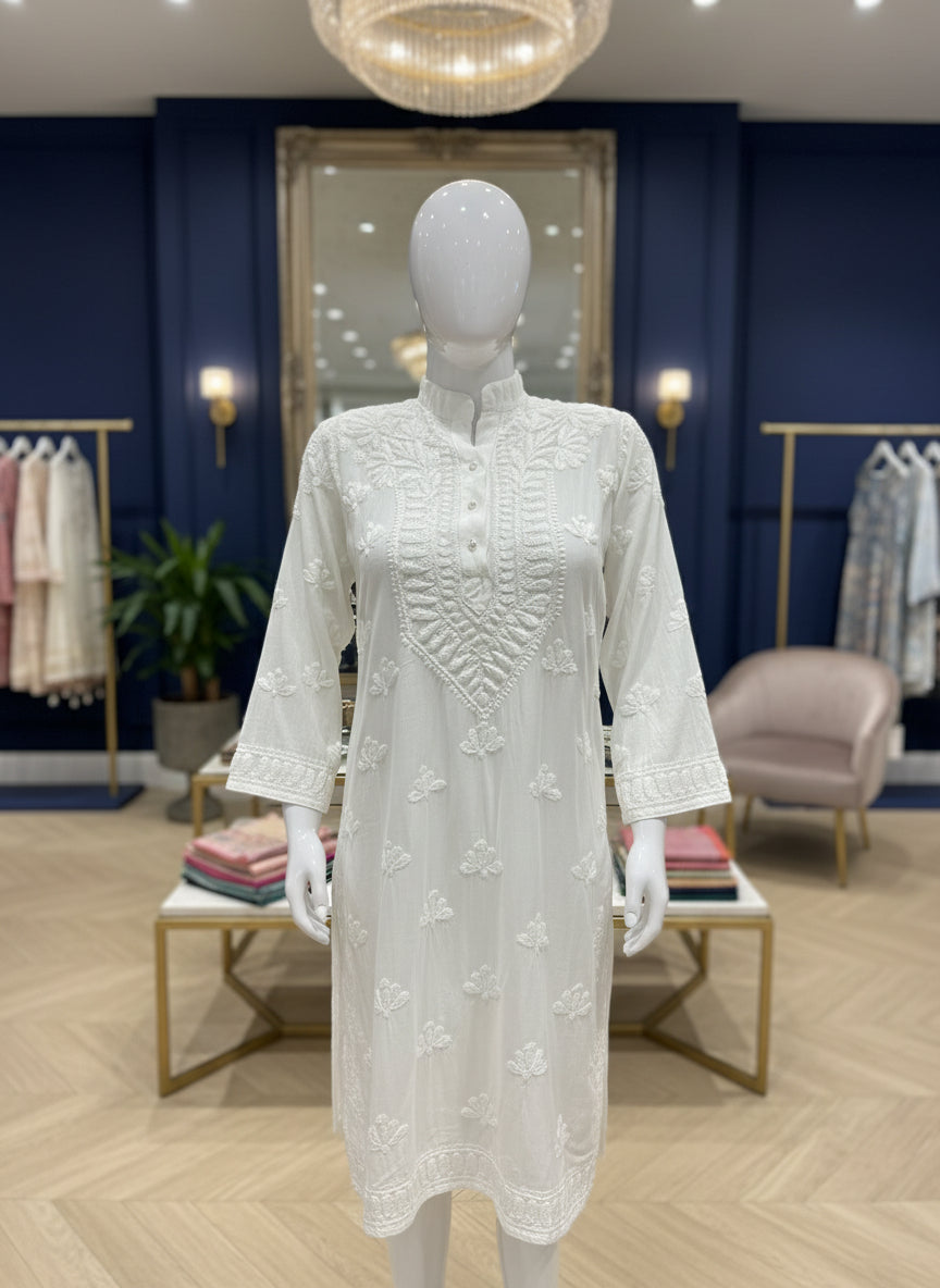 A whiteMuslin fabricwith collar Chikankari short length kurti and three buttons on the front, featuring intricate ghasspati hand embroidery with floral motifs by famaza couture