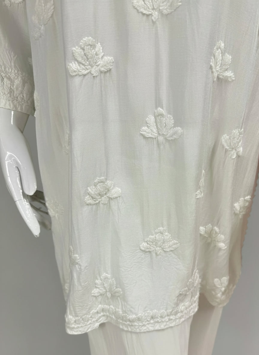 A white colour Muslin fabricwith collar Chikankari short length kurti and three buttons on the front, featuring intricate ghasspati hand embroidery with floral motifs by famaza couture