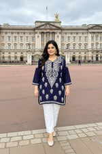 A woman modelling a navy blue kurta with intricate white embroidery, standing in front of Buckingham Palace.