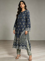 A woman modelling a navy blue three-piece kurta set with beige floral prints and lace trim, paired with matching pants and beige high-heeled sandals, set against a neutral studio background.
