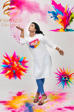 A woman wearing a white cotton kurti with Schiffli Chikankari embroidery, celebrating Holi with colourful powder in the air around her.