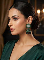 A women wearing the Elegant black brass jhumka earrings featuring a refreshing mint green stone floral stud and matching mint stone inlay on the jhumka dome.
