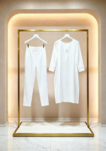 Hanging display of the white handcrafted sleeveless Chanderi silk Chikankari co-ord set, featuring the tunic and matching trousers hanging side-by-side on white hangers within an illuminated gold boutique rack.