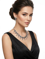 Model wearing an antique oxidized silver sunflower-motif necklace set featuring clear crystal centers and traditional triple-bead ghungroo drops on a silver dory cord.