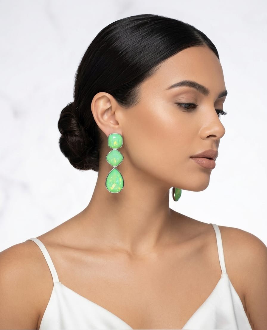 The earrings feature a vibrant, shimmering lime-green iridescent finish with geometric cushion-cut and teardrop-shaped stones in a silver-tone setting.