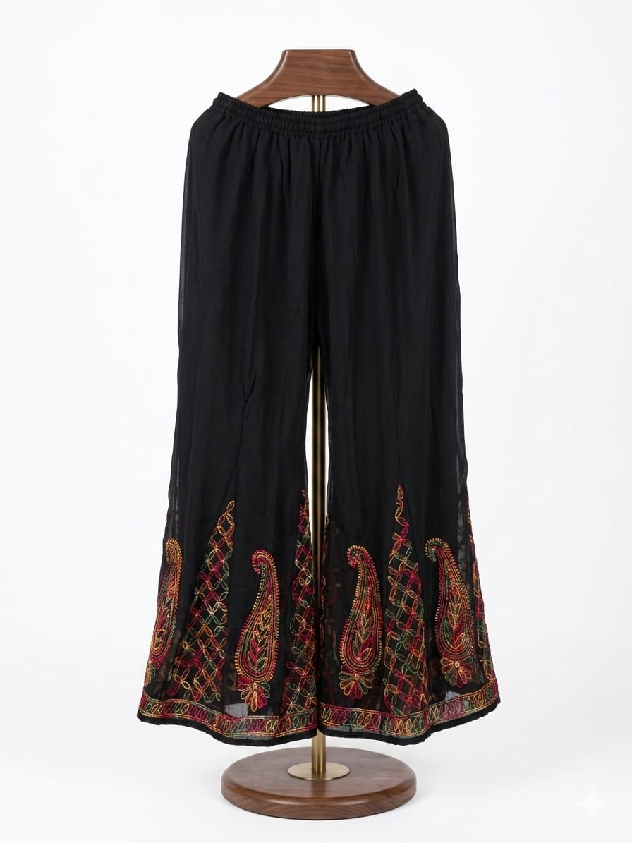 Front view of a black georgette wide-leg sharara featuring vibrant multi-thread paisley embroidery at the hem, displayed on a wooden mannequin.