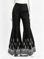 Black bell-bottom pants with white lace trim on a mannequin against a white background