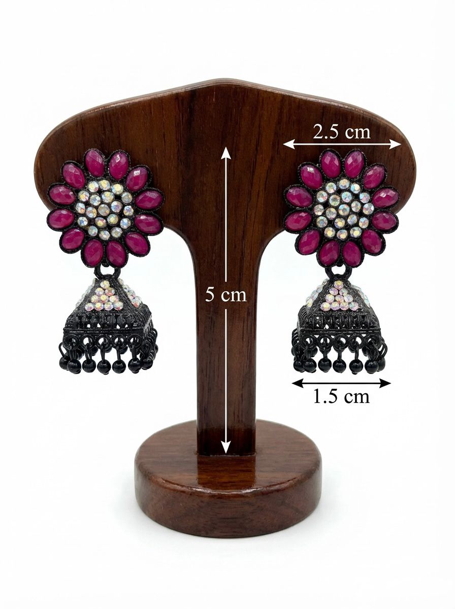 Black brass jhumka earrings featuring a vibrant magenta-pink stone floral stud and a matching stone-accented bell-shaped jhumka base.