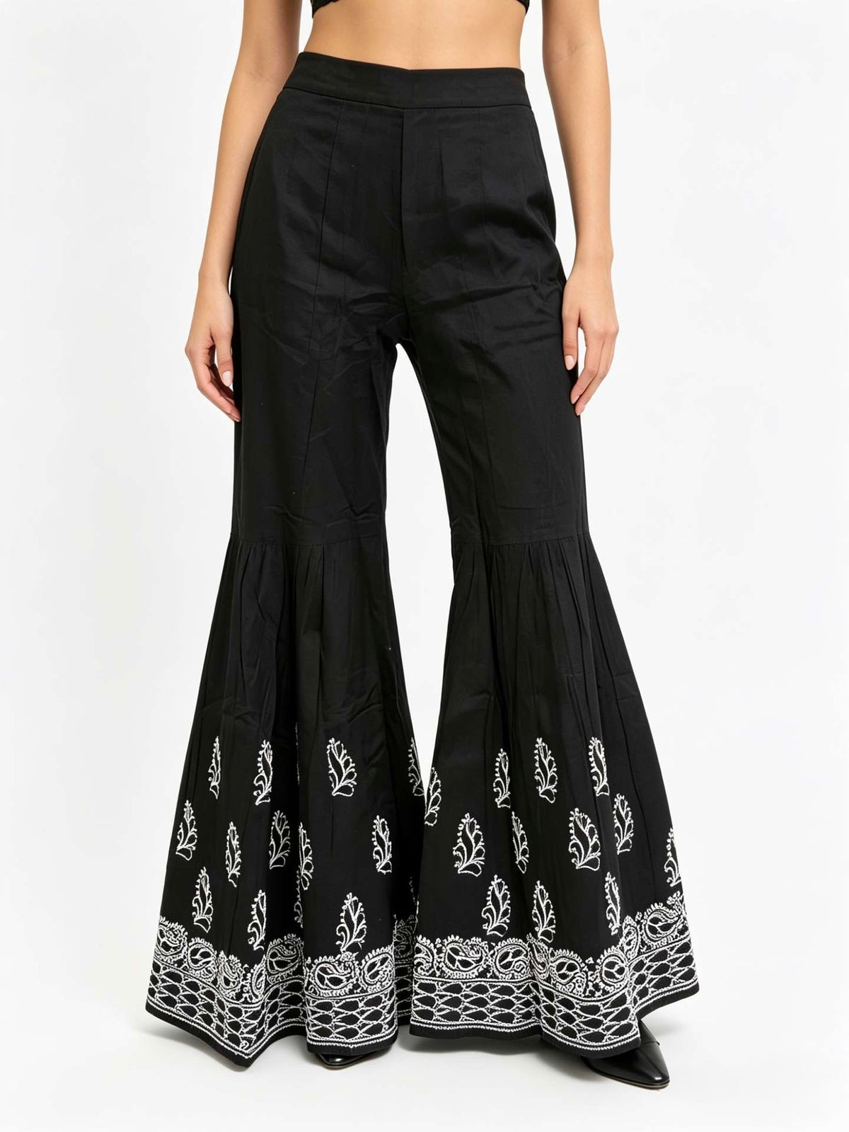 Black flared pants with white embroidery on a white background