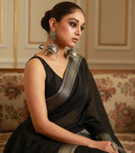 Woman wearing large ornate earrings with a blurred background