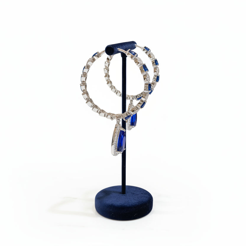 round earrings and blue pendant on a stand in a store setting.