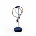 round earrings and blue pendant on a stand in a store setting.