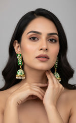 Bottle Green colour pair of gold-platedMeenakari drop Jhumka earrings displayed on a stand, featuring intricate designs and studded with stones.