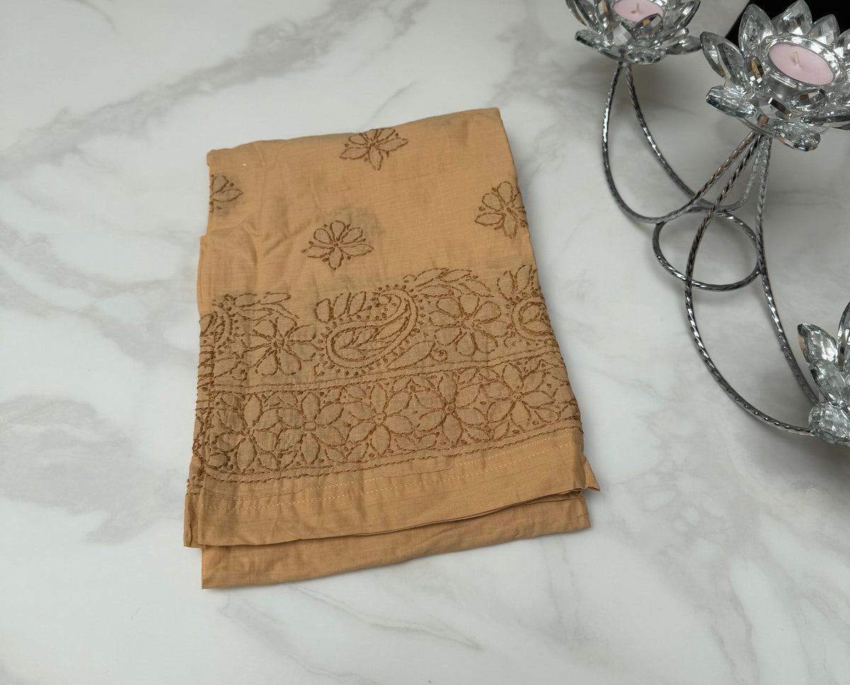 Brown embroidered fabric on a marble surface with decorative elements above