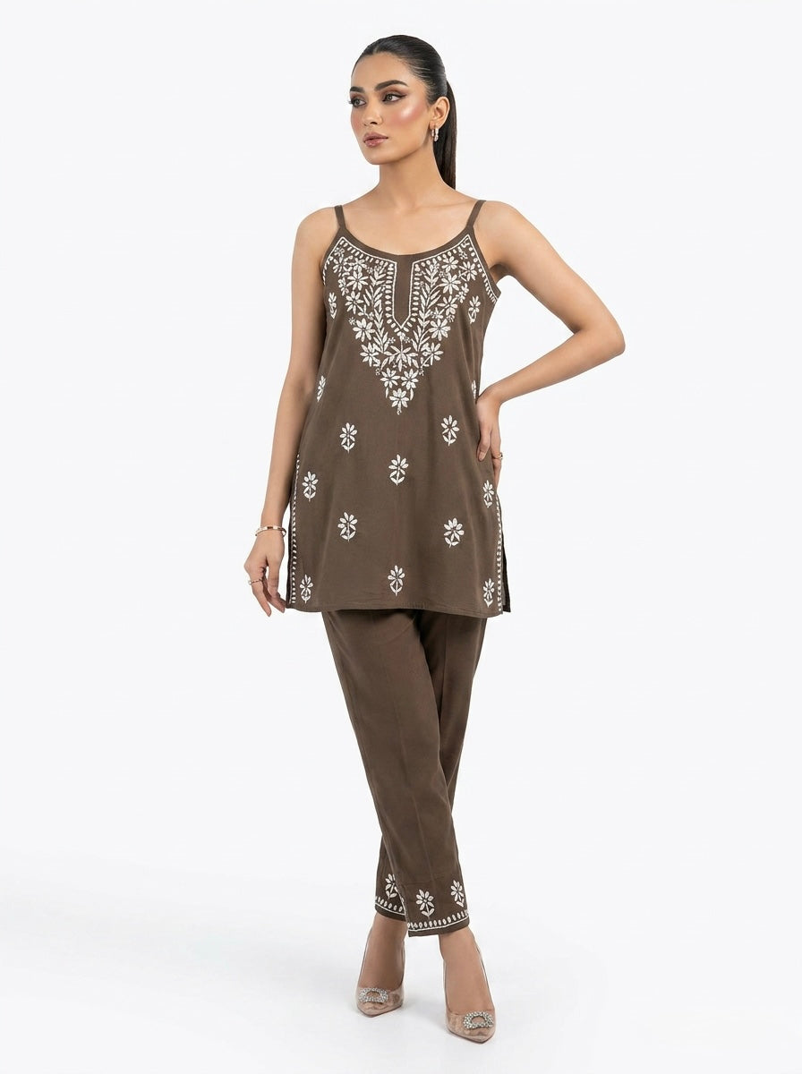 Woman wearing a brown embroidered outfit on a white background