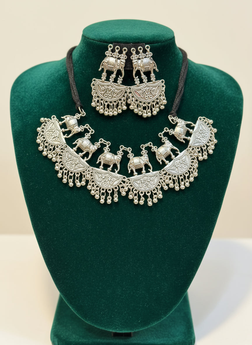 Silver elephant-themed necklace and earrings set on a black mannequin.