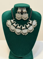 Silver elephant-themed necklace and earrings set on a black mannequin.