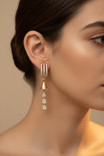 Close-up of 4cm rose gold finish earrings featuring a triple-row arched stud and a cascading tiered teardrop drop.