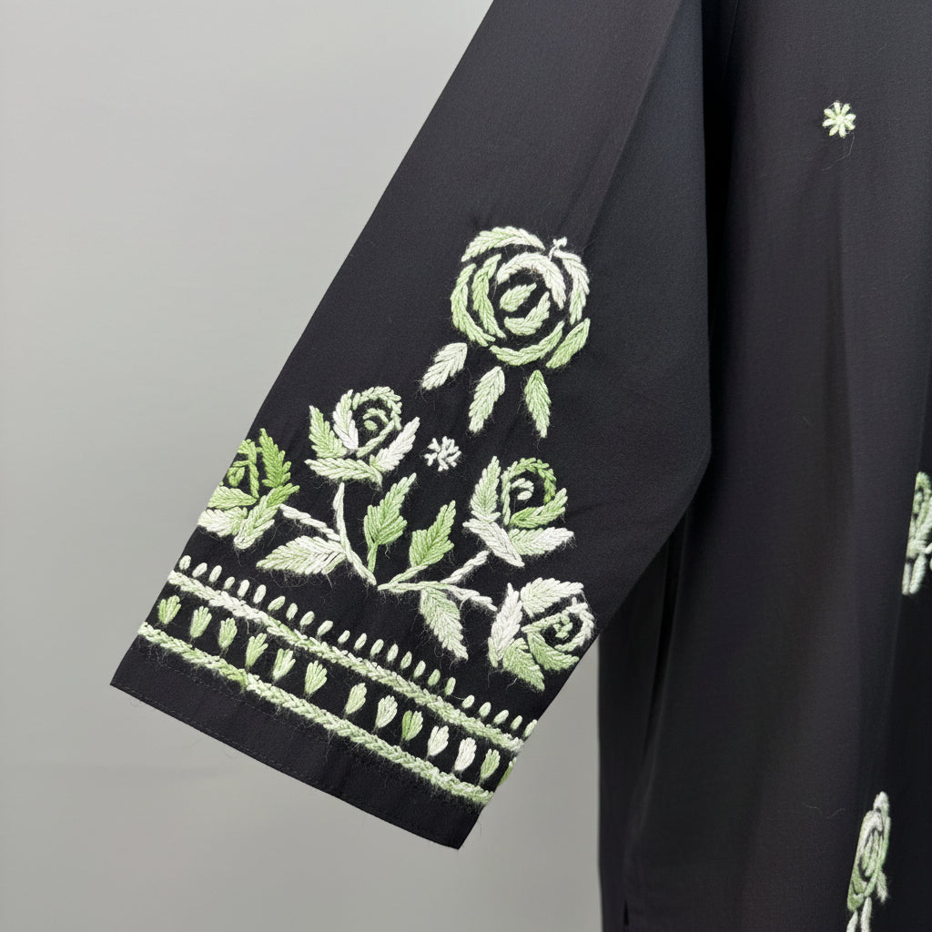 Close-up of a black sleeves featuring detailed green and white floral embroidery on the sleeve, with rose motifs and decorative border stitching.