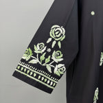 Close-up of a black sleeves featuring detailed green and white floral embroidery on the sleeve, with rose motifs and decorative border stitching.