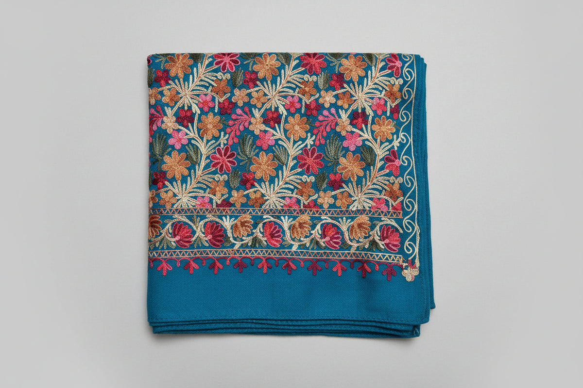 Close-up of a blue Kashmiri embroidered pashmina scarf with floral patterns and tassels detail.