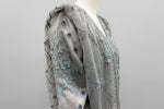 Close-up of a grey fabric with blue embellishments on a mannequin.