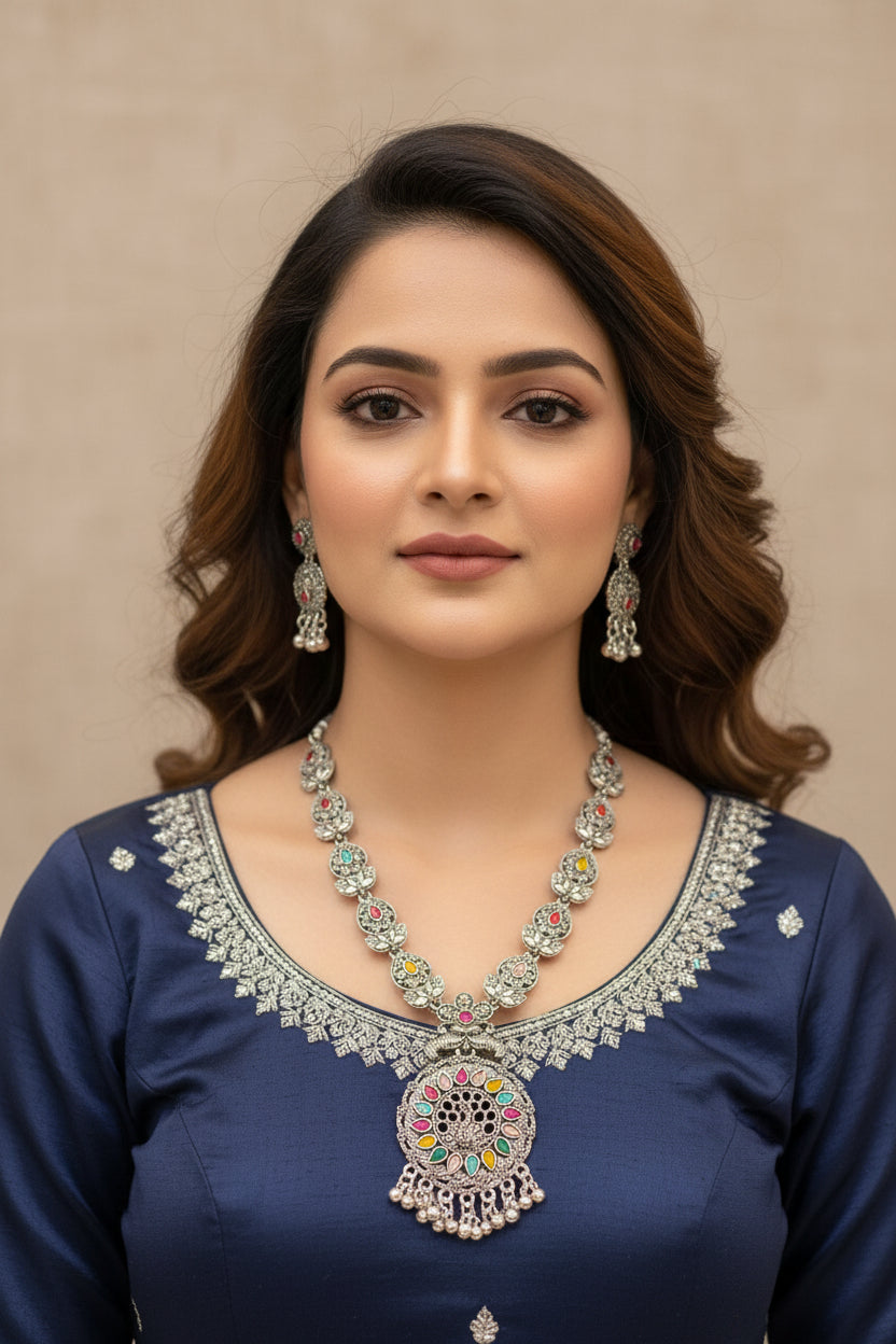 Close-up of a woman wearing a heavy oxidised brass necklace featuring a vibrant multicolor pendant and matching earrings.