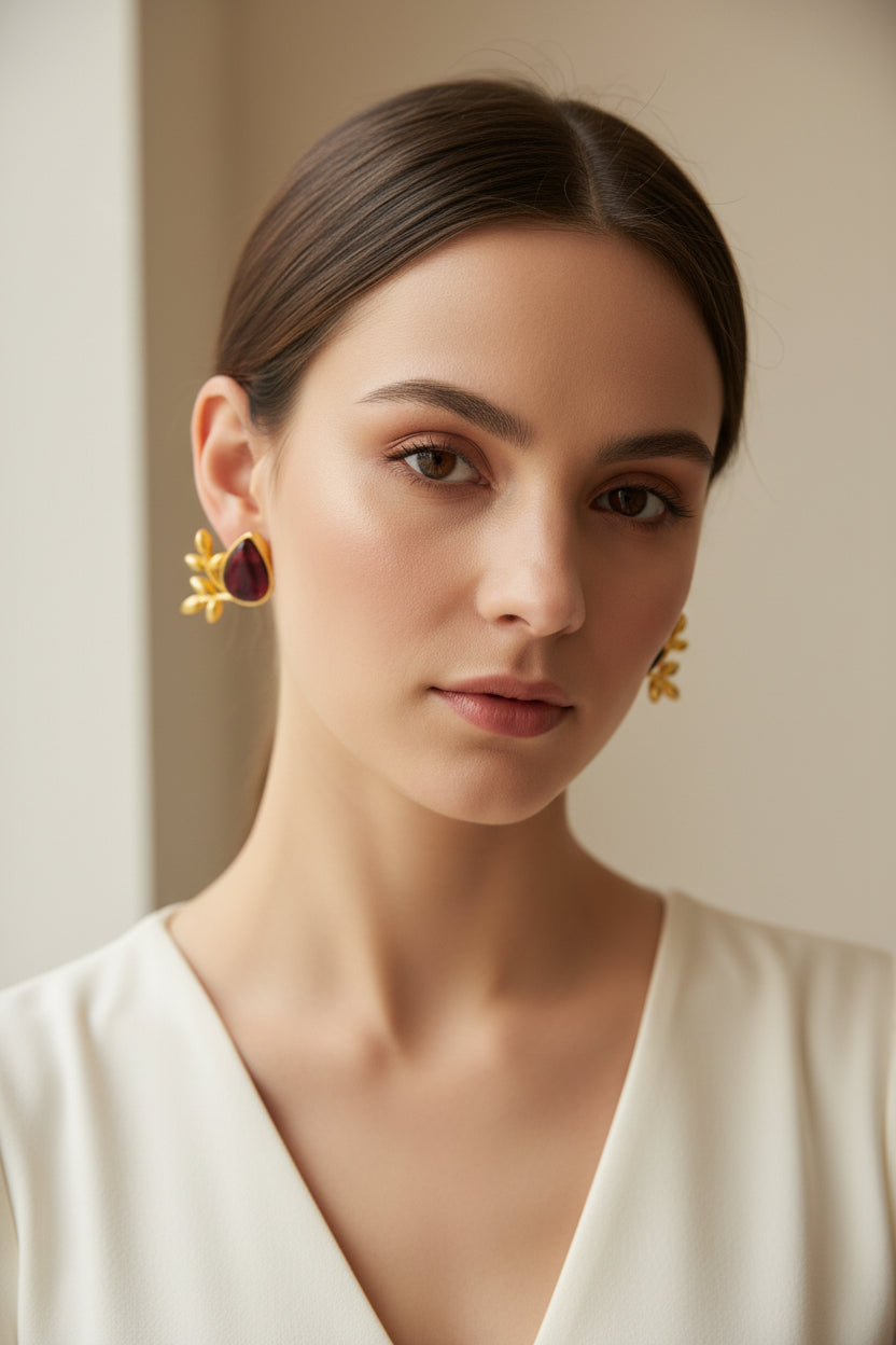 Close-up of a woman wearing a maroon stone and gold earring