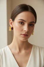 Close-up of a woman wearing a maroon stone and gold earring