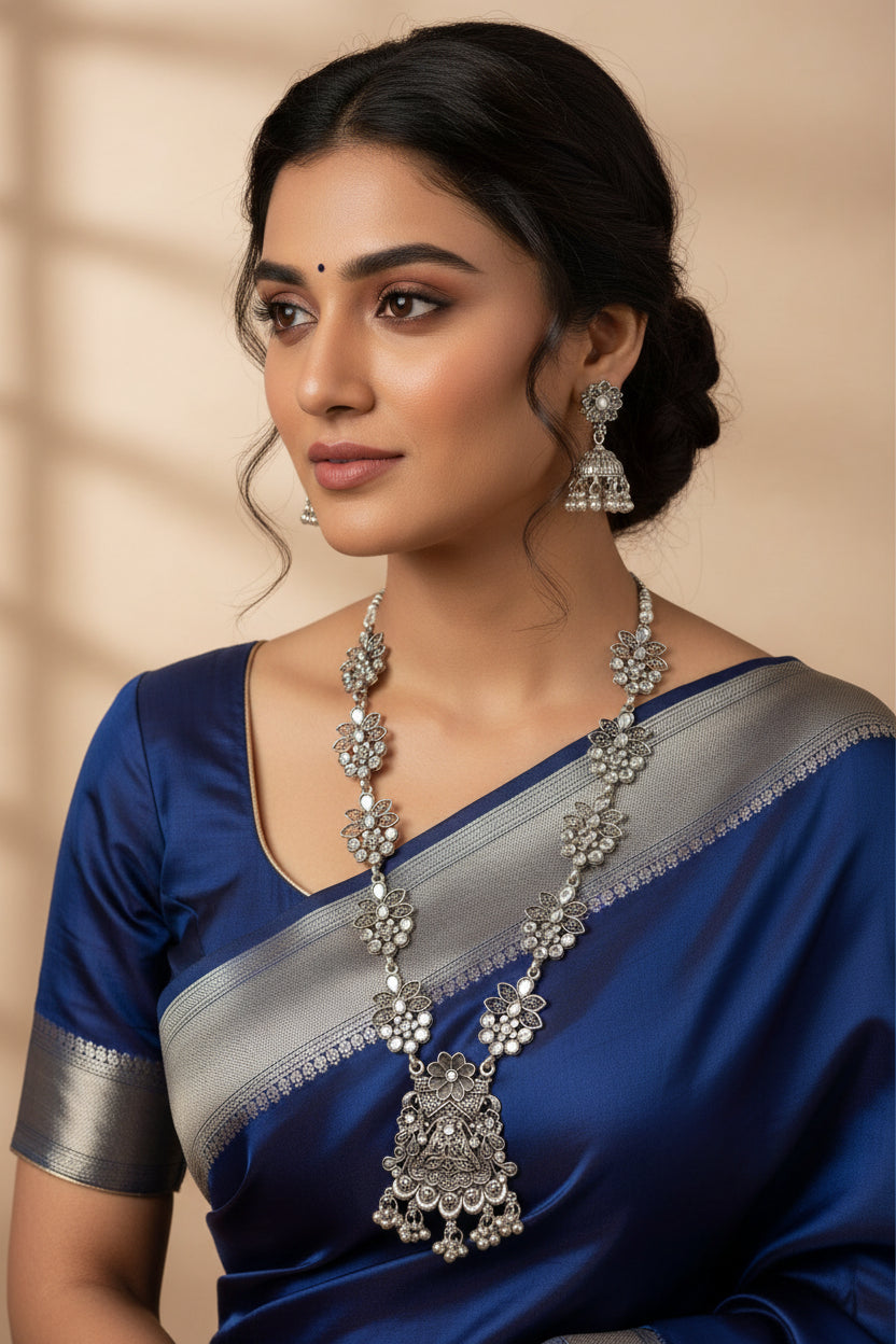 Close-up of a woman wearing oxidised long necklace with a large floral pendant and matching jhumka-style earrings.