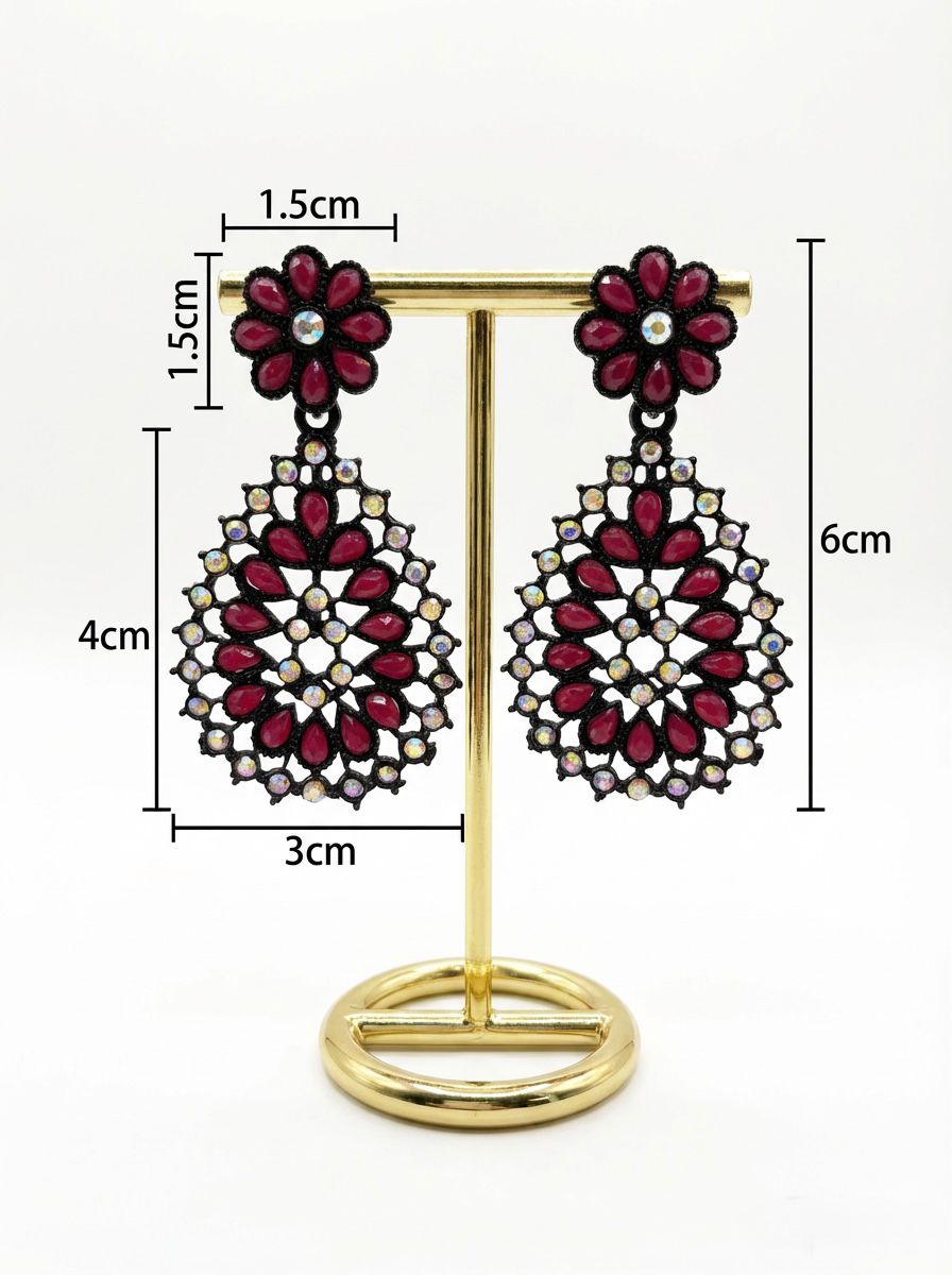 Close-up of black brass teardrop earrings with a vibrant red stone floral stud and matching red stone inlay throughout the teardrop base.